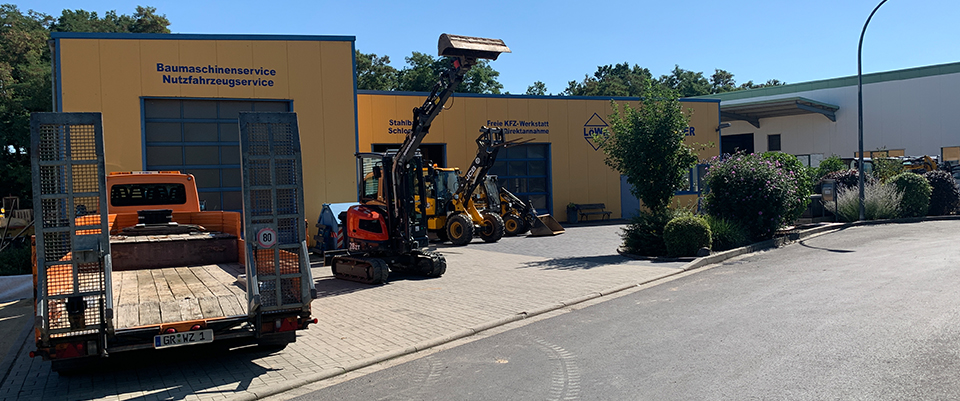LöWa-Hof mit Tieflader, Minibaggern und Radlader vor den Werkstatthallen.